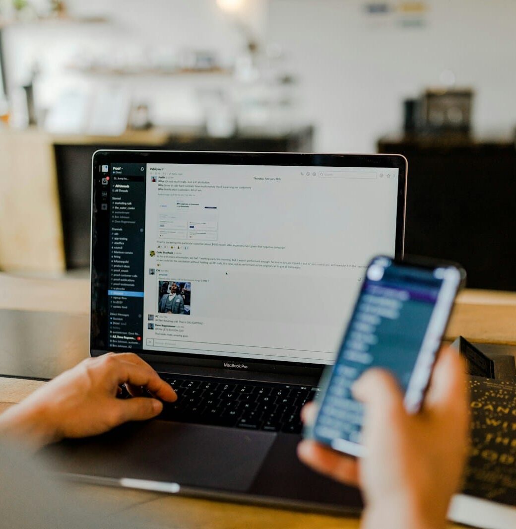 person using phone and laptop