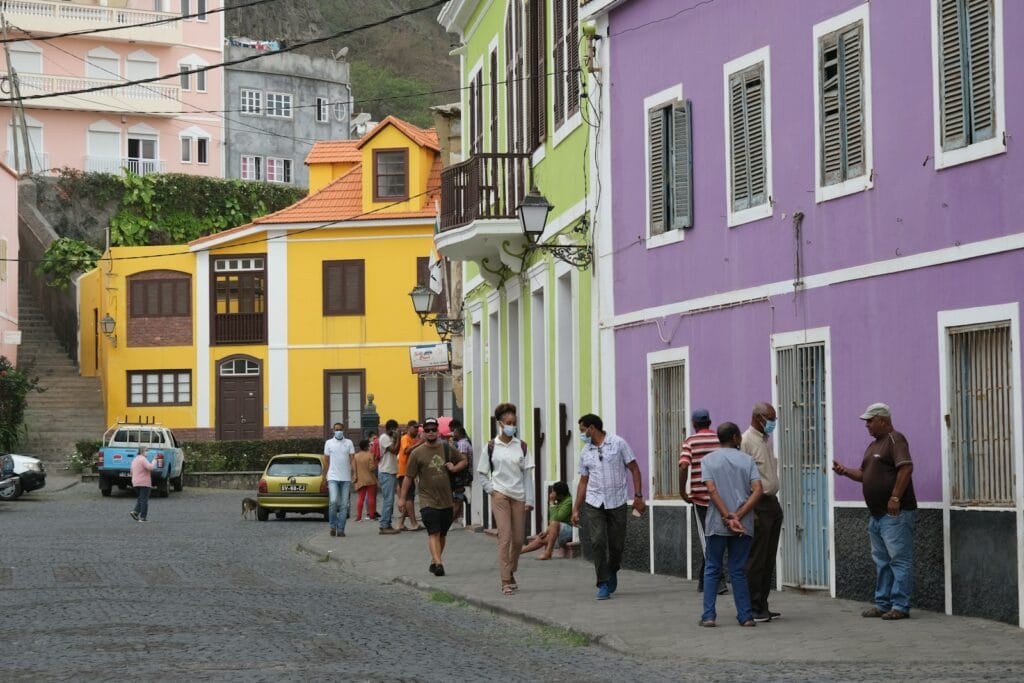 a group of people walking down a street next to colorful buildings_ribeira grande_santo_antão